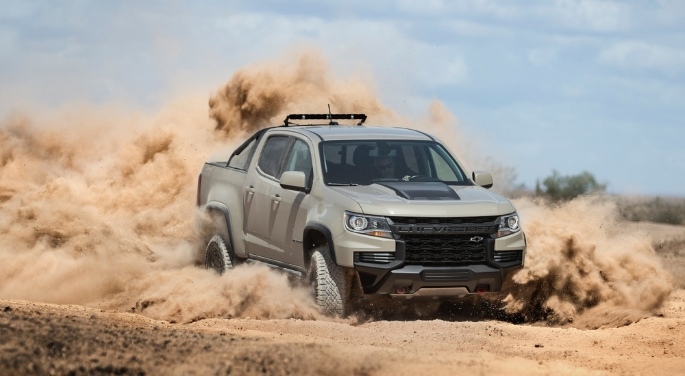 A tan Chevy truck, the 2021 Chevy Colorado ZR2, is shown off-roading.