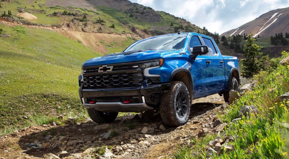 blue 2022 Chevy Silverado 1500 ZR2 off-roading on a rocky mountain trail.