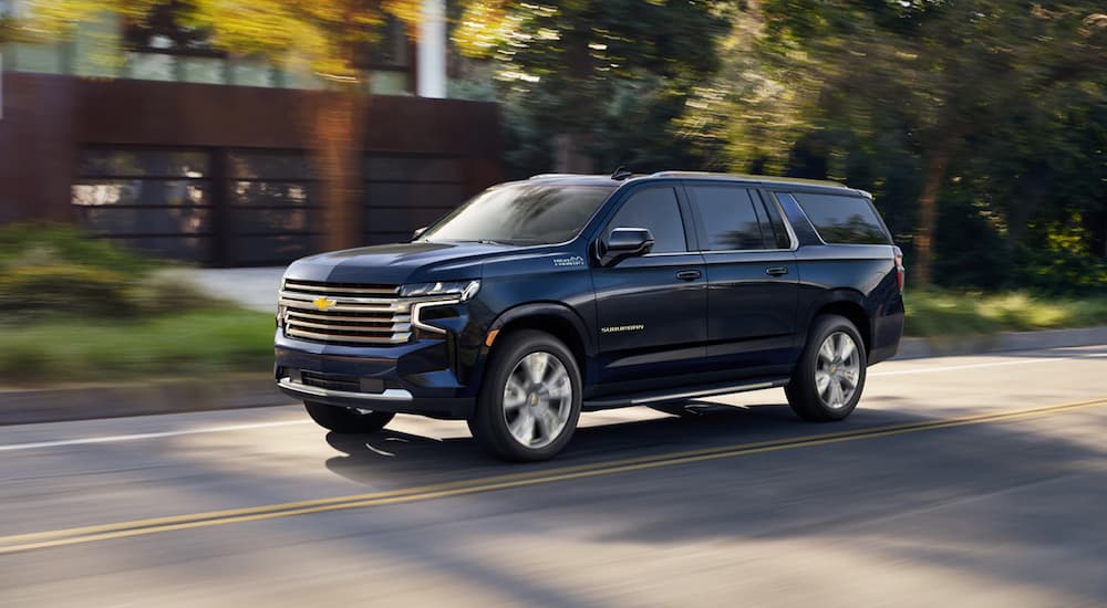 A dark blue 2022 Chevy Suburban is shown driving on a street after visiting a Selmer SUV dealer.