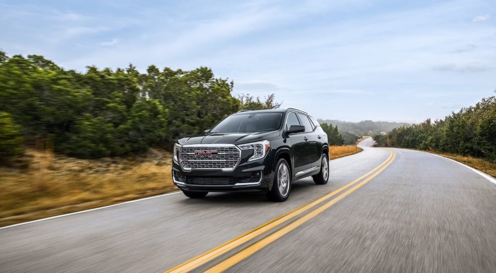 A black 2022 Terrain Denali is shown driving on an open road after looking at used GMC SUVs for sale.