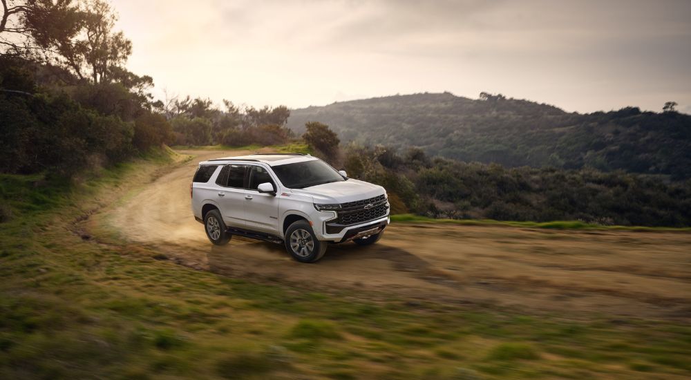 A white 2021 Chevy Tahoe Z71 is shown kicking up dust on the way to look at used SUVs for sale.