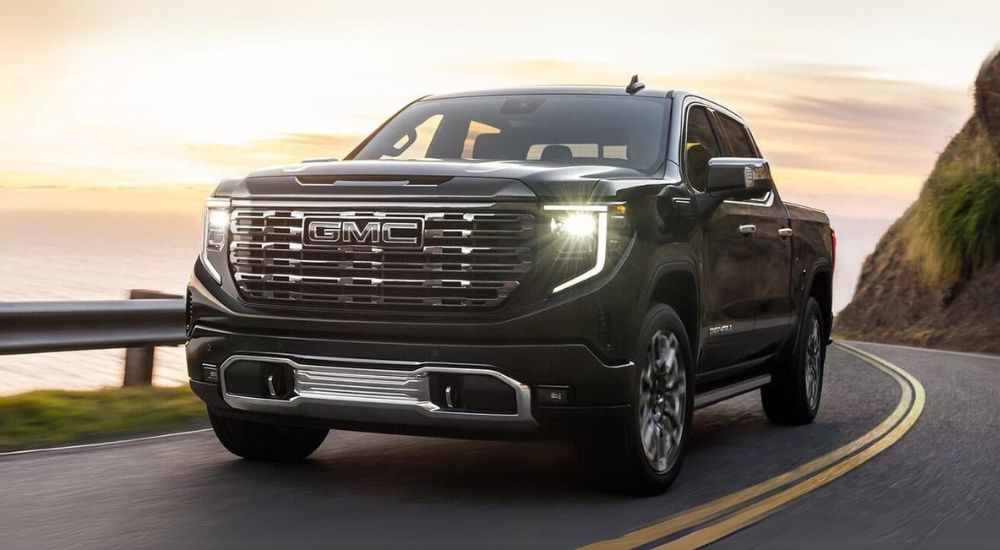 A black 2024 GMC Sierra 1500 Denali Ultimate is shown driving on a highway.