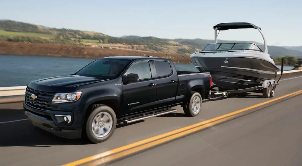A black 2021 Chevy Colorado is shown towing a boat.