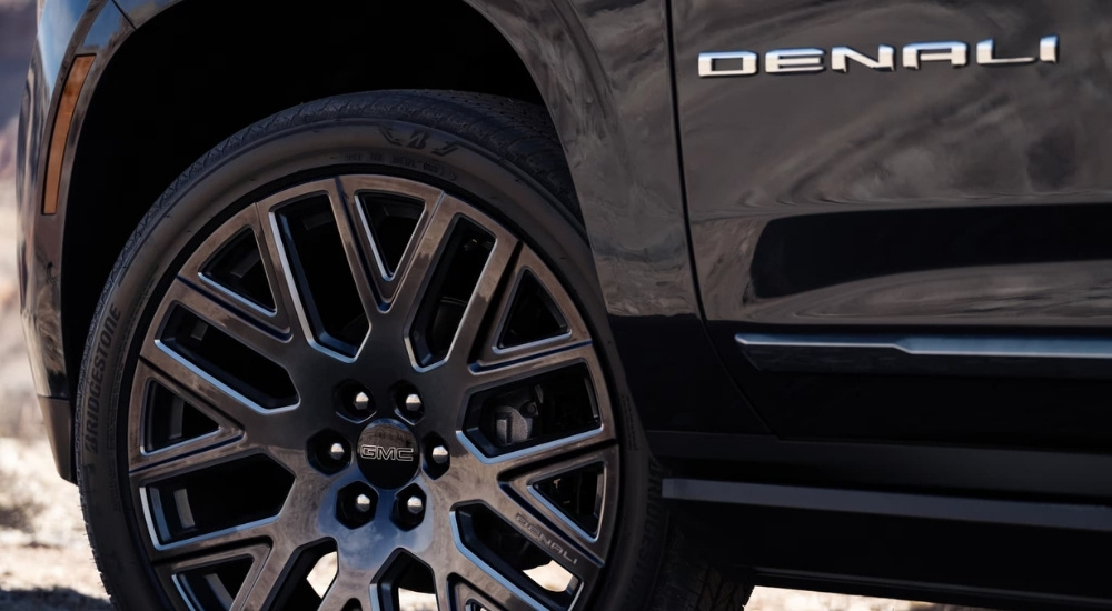 A close-up shows a wheel on a black 2025 GMC Yukon Denali.