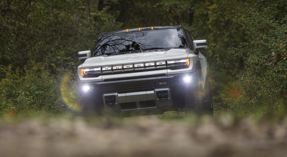 A white 2025 GMC Hummer EV is shown driving to a GMC dealer near Iuka.