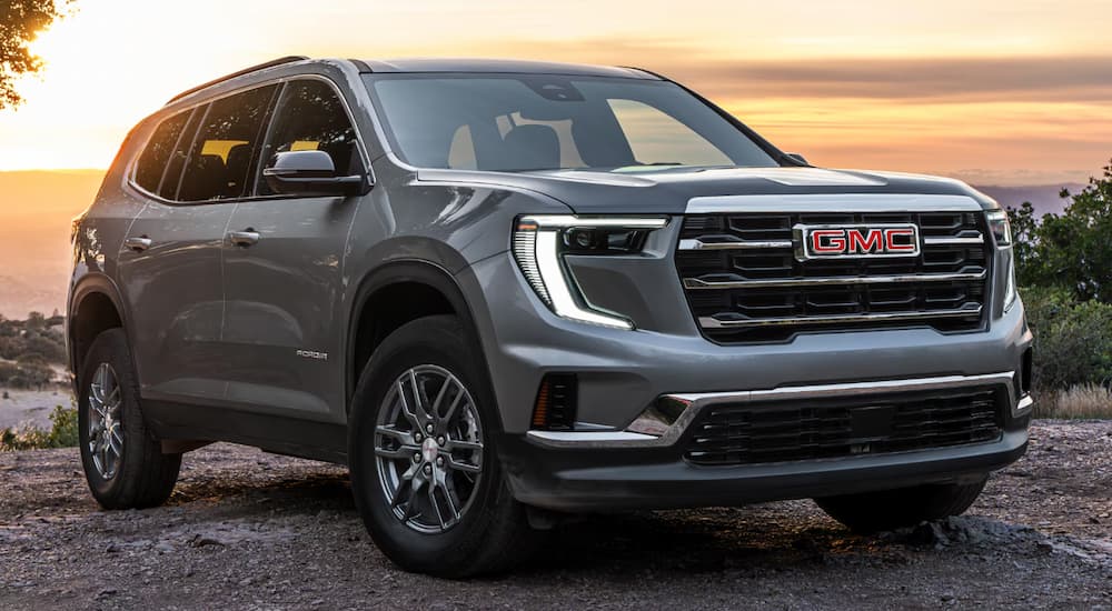 Grey 2025 GMC Acadia parked off-road on dirt.