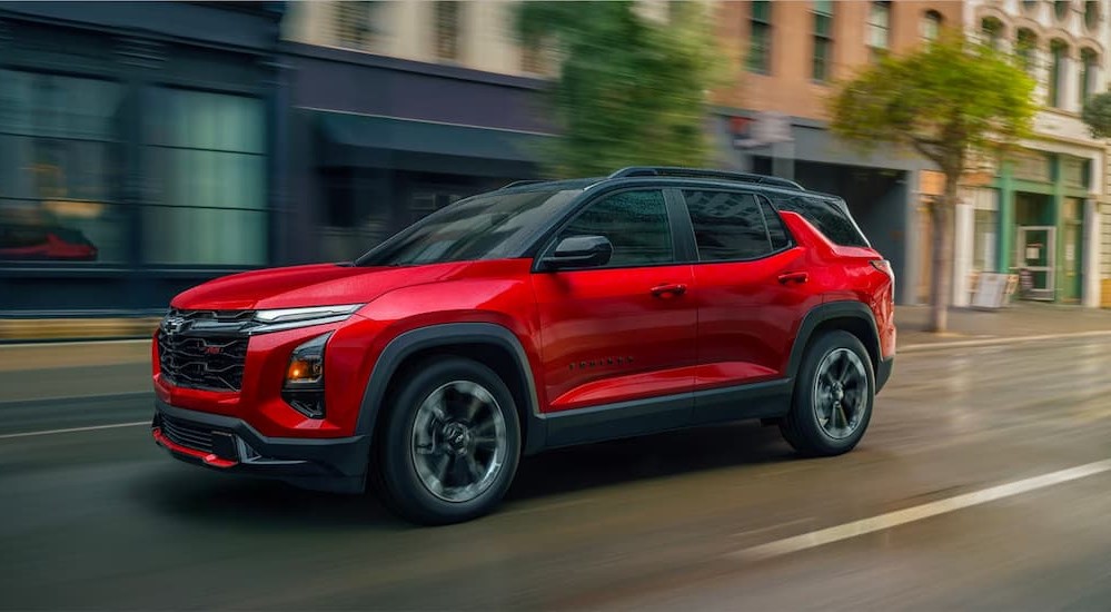 A red 2026 Chevy Equinox RS driviing in a city.