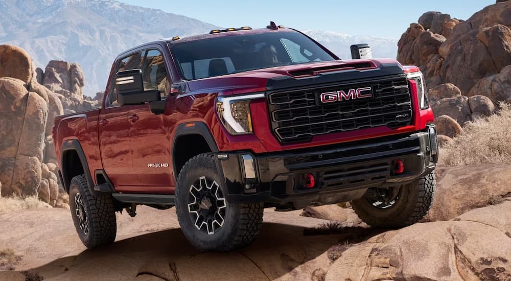 Red 2024 GMC Sierra 2500 HD driving through a desert.