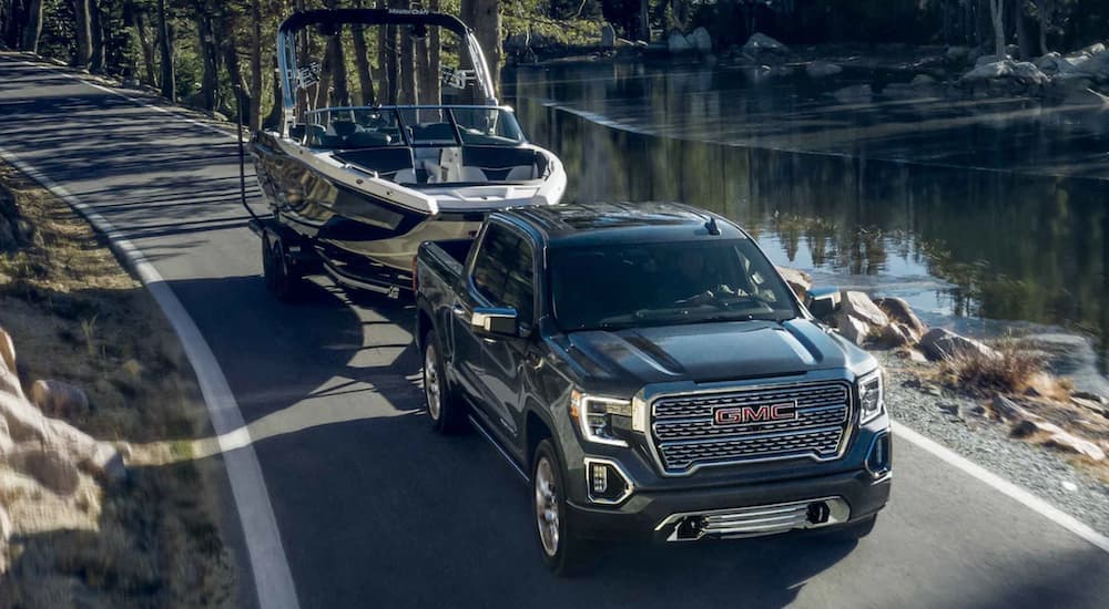 A black 2022 GMC Sierra 1500 towing a boat after viewing used GMC trucks for sale.