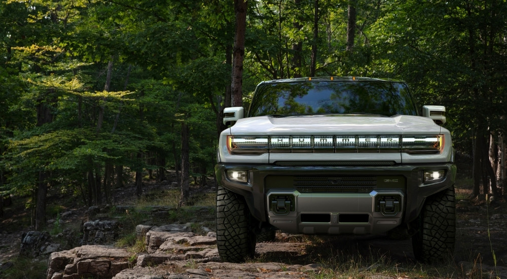 A white 2022 GMC Hummer EV is shown parked in the woods.