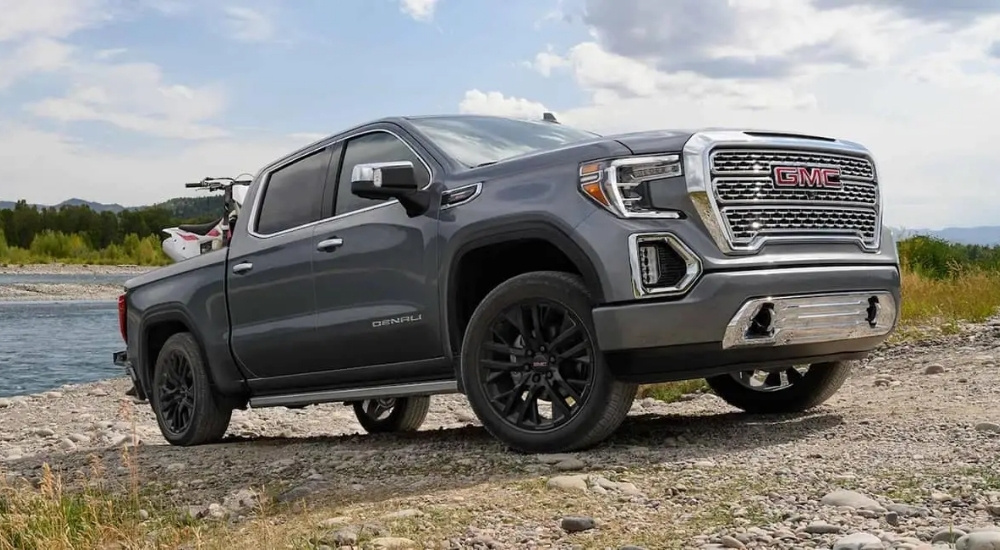 A silver 2021 GMC Sierra 1500 Denali parked on a hill with an ATV in the bed.