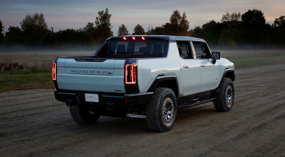 A white 2022 GMC Hummer EV driving down a dirt path at dusk.