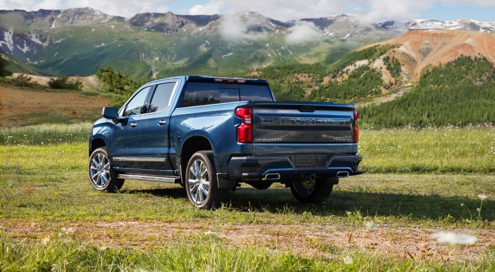 A dark blue 2022 Chevy Silverado 1500 High Country is parked on a field.