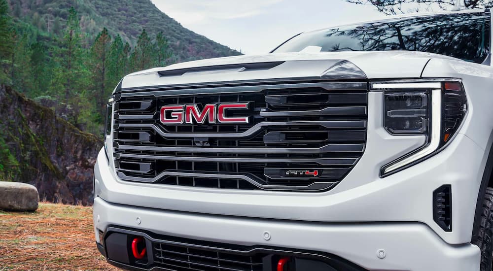 A close-up shows the driver side headlight on a white 2022 GMC Sierra 1500 AT4.