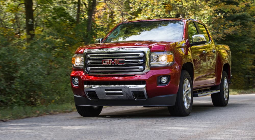 Red 2019 GMC Canyon SLT  driving on a tree-lined road