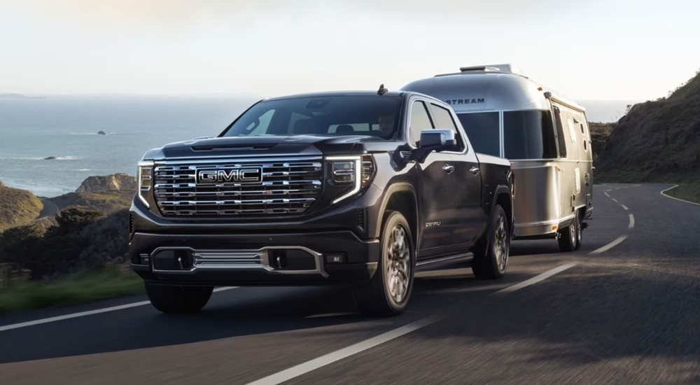 A black 2023 GMC Sierra 1500 Denali Ultimate is shown towing a silver airstream trailer.