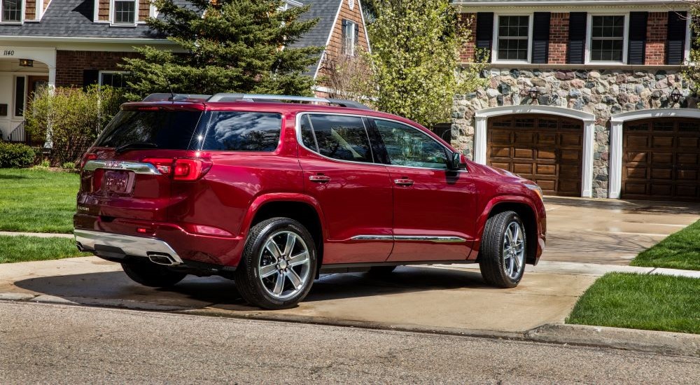 A red 2018 GMC Acadia Denali is shown from the side parked on a driveway.