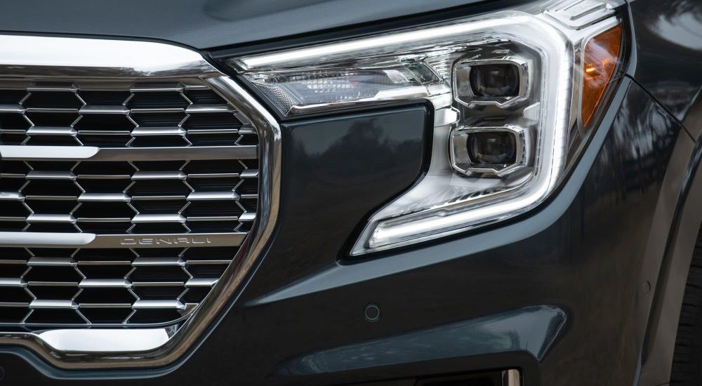 A close up shows the driver side headlight on a black 2024 GMC Terrain Denali.