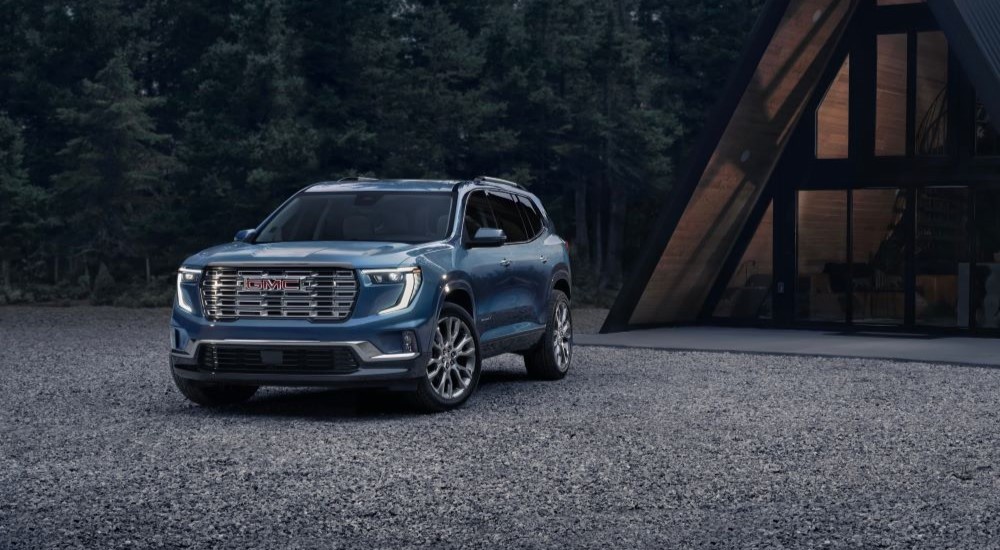 A blue 2024 GMC Acadia Denali is shown parked off-road.