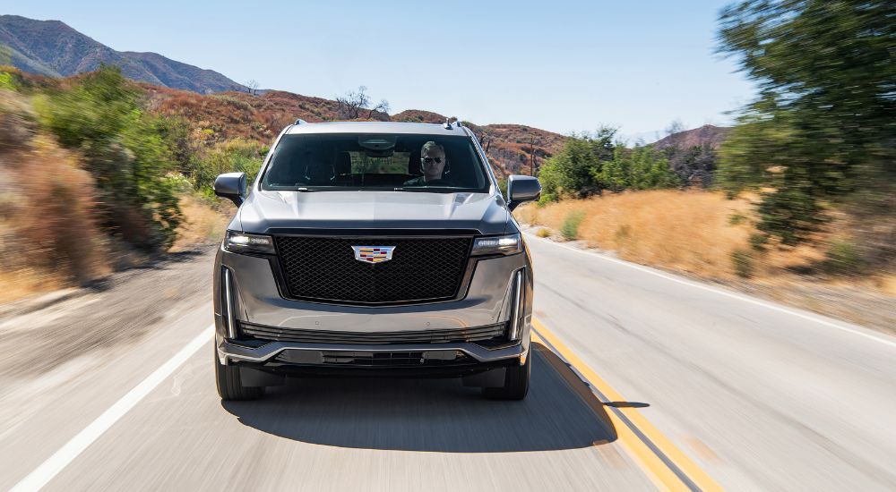 A silver 2021 Cadillac Escalade is shown driving on an open road.