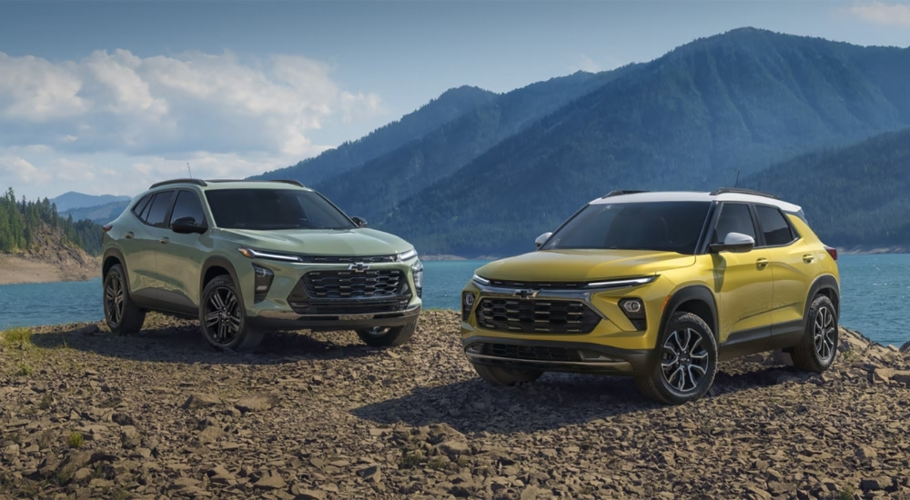 A green 2025 Chevy Trax ACTIV and a yellow Trailblazer ACTIV are shown near a lake.