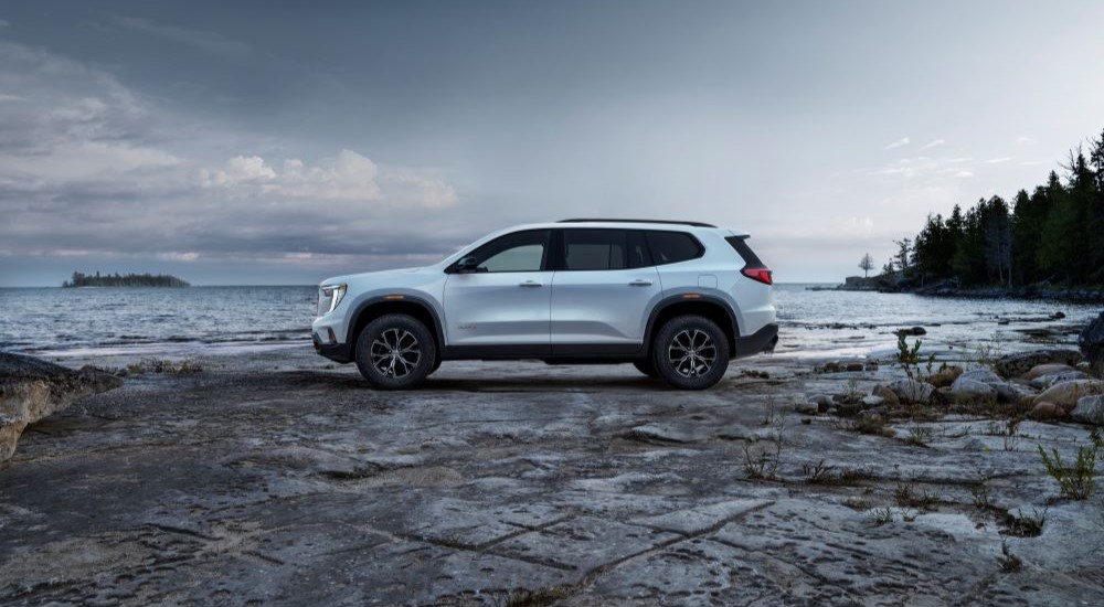 A white 2025 GMC Acadia AT4 parked near a lake
