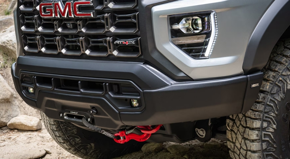 A close-up shows a winch on a silver 2025 GMC Canyon AT4X AEV.