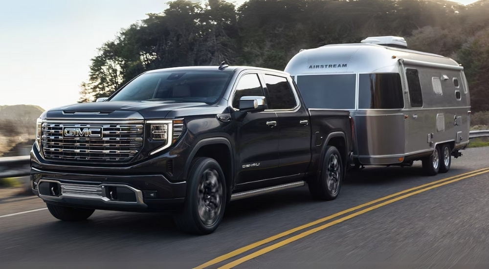 A black 2025 GMC Sierra 1500 for sale near Ripley towing an Airstream trailer on the highway.