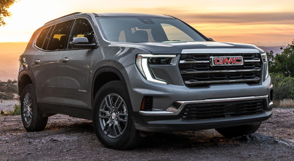 Grey 2025 GMC Acadia parked off-road on dirt.