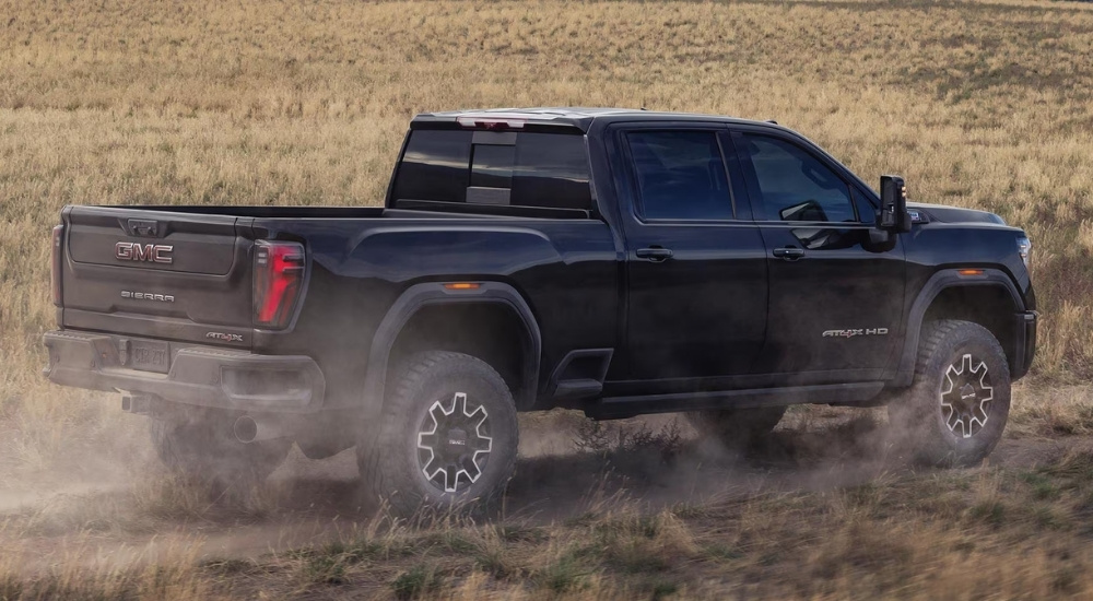 Black 2026 GMC Sierra 2500 HD AT4X kick up dust on a trail