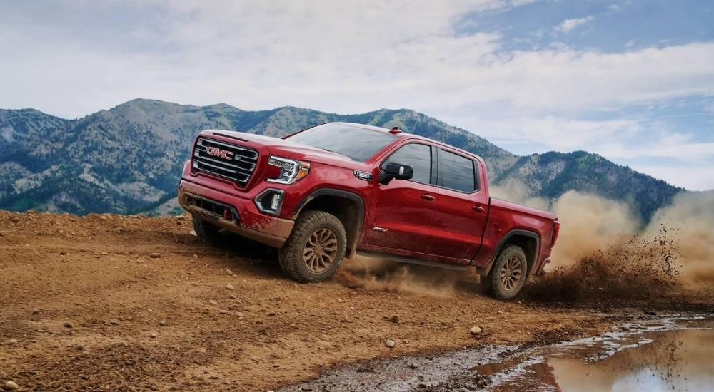 A red 2021 GMC Sierra 1500 is shown off-roading in the mountains.