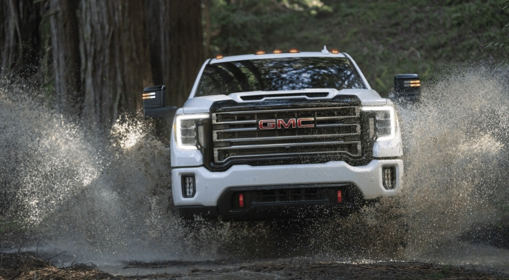 A white 2021 GMC Sierra 2500 HD AT4 is shown splashing through water.