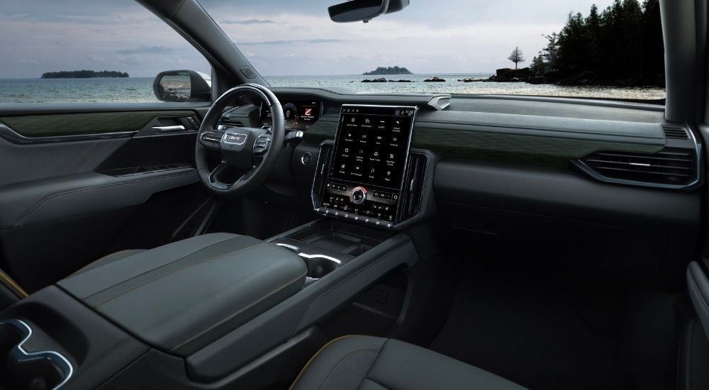The black interior of a 2024 GMC Acadia AT4 is shown from the passenger seat.