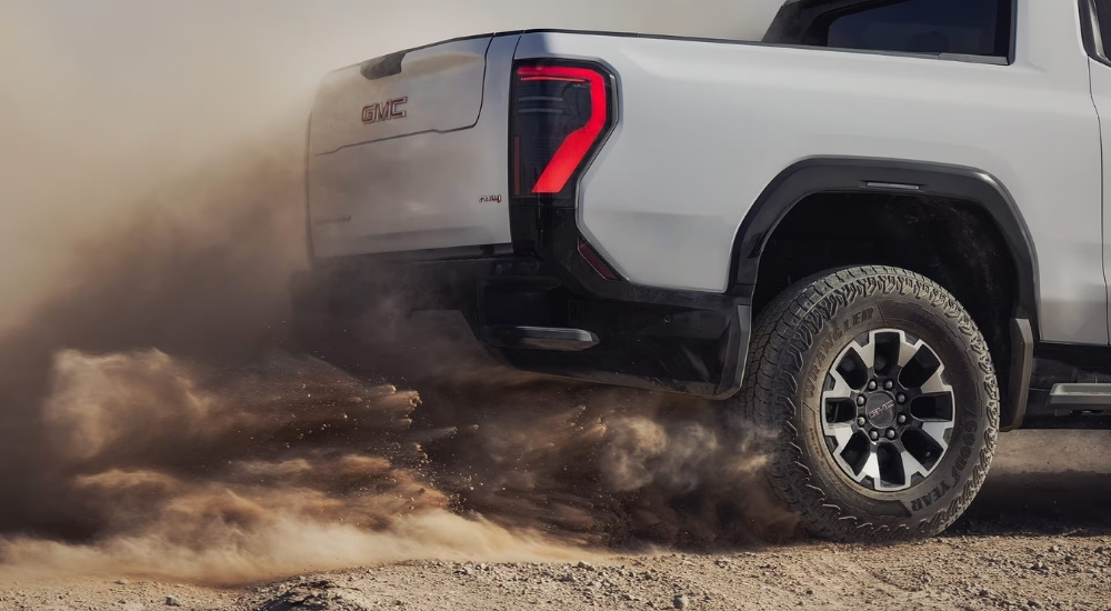Rear wheel on a grey 2026 GMC Sierra EV AT4 kicking up dust