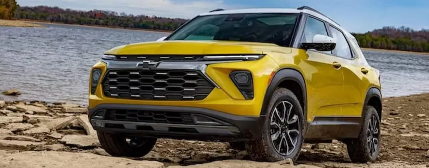 A yellow 2024 Chevy Trailblazer is shown parked near a lake.