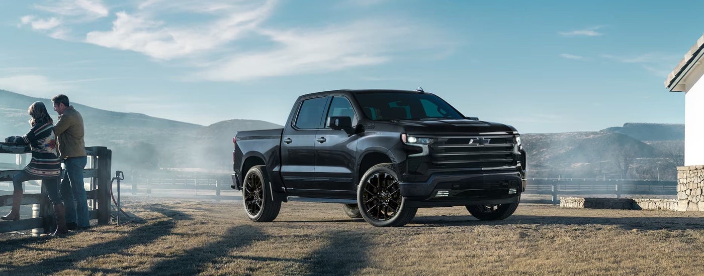 A black 2025 Chevy Silverado 1500 High Country Black Edition is shown parked on a ranch.