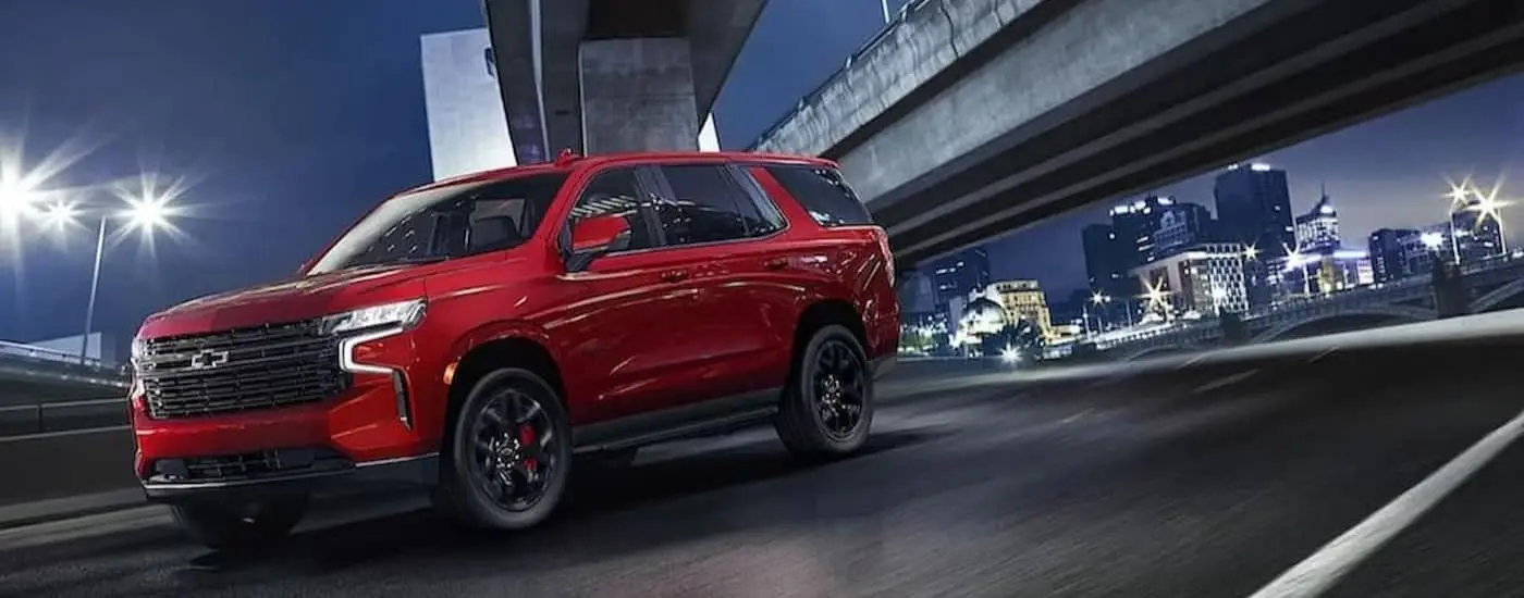 A red 2024 Chevy Tahoe is shown driving under and overpass.