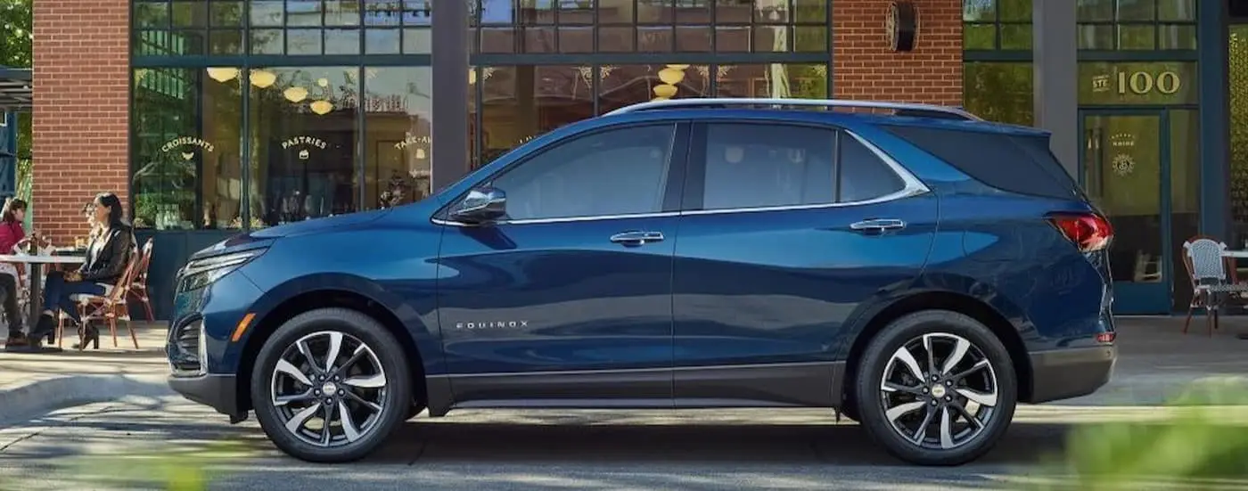 A blue 2023 Chevy Equinox is shown parked near a brick building.