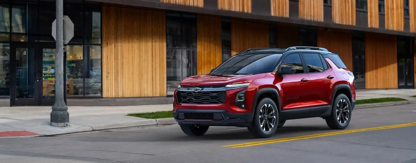 A red 2025 Chevy Equinox RS is shown driving to a Chevy dealer near Iuka.