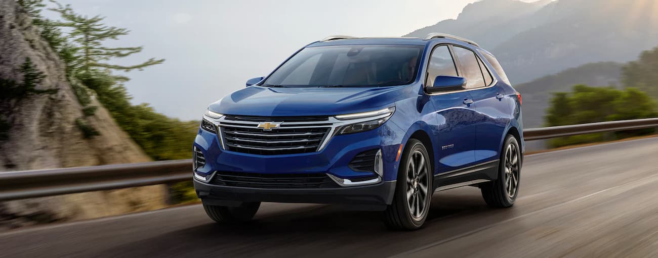 A dark blue 2022 Chevy Equinox is shown driving on a mountain highway.