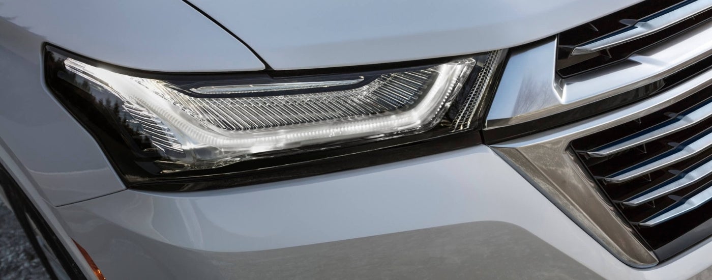 A close-up shows the passenger side headlight on a silver 2022 Chevy Traverse.