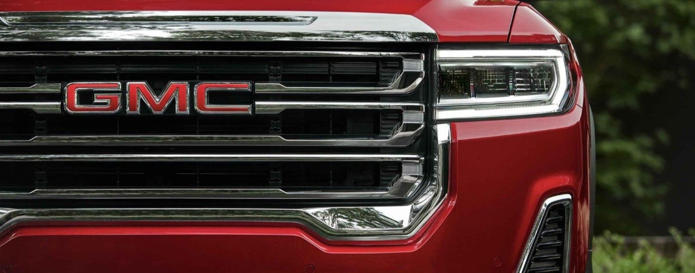 A close up shows the grille and driver side headlight on a red 2021 GMC Acadia.