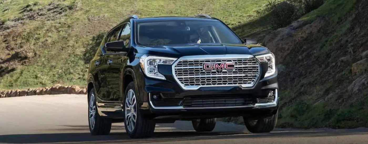A black 2024 GMC Terrain is shown driving uphill.
