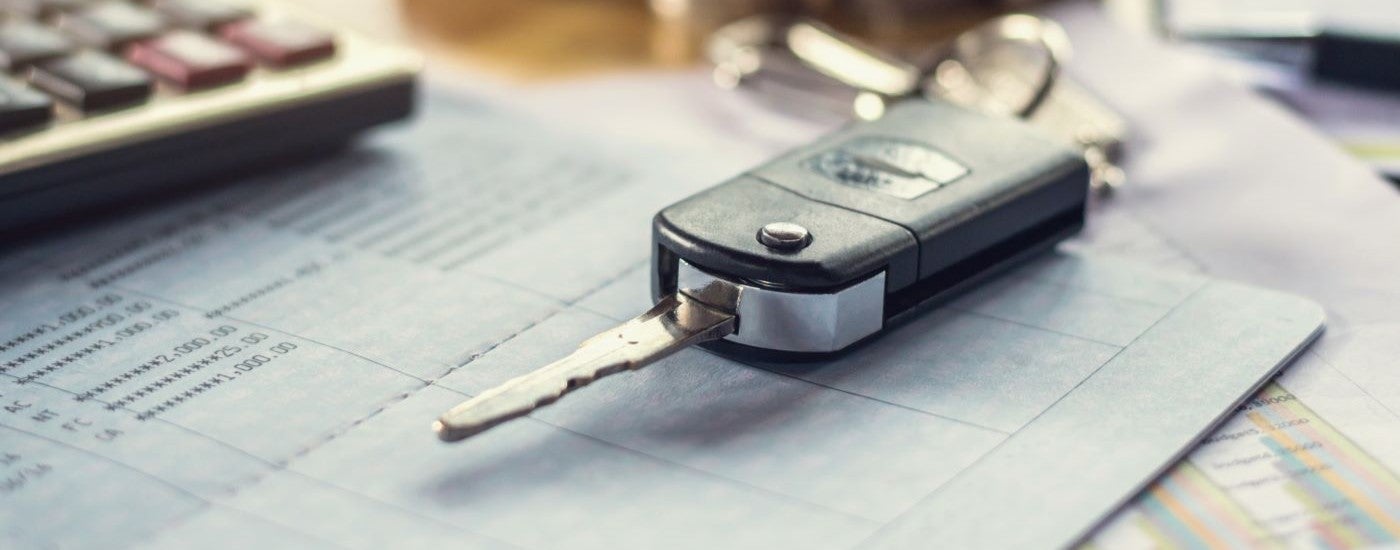 A close-up shows a car key on a desk.