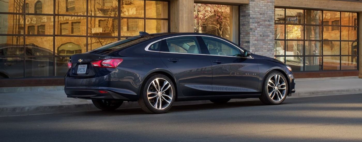 A black 2022 Chevy Malibu is shown from the side on a city street.