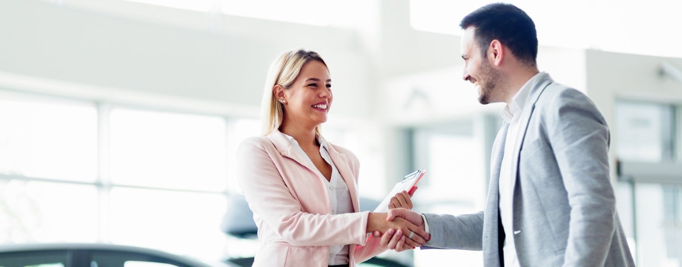 A customer and salesperson shake hands while they sell their car.