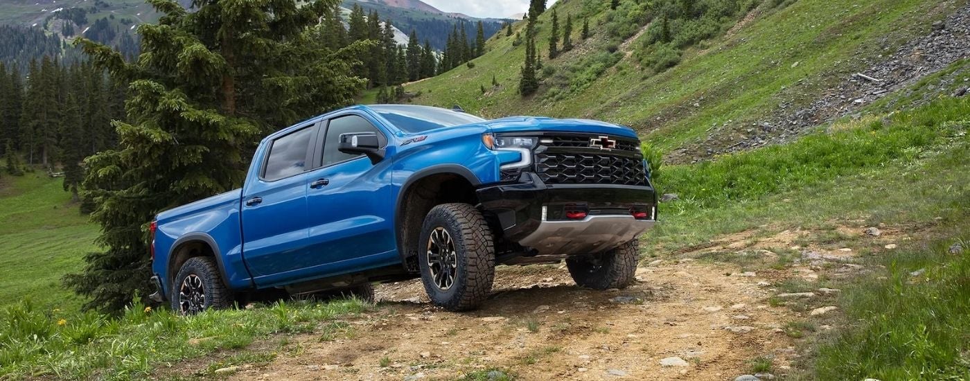 A blue 2022 Chevy Silverado 1500 ZR2 driving over a trail crest.