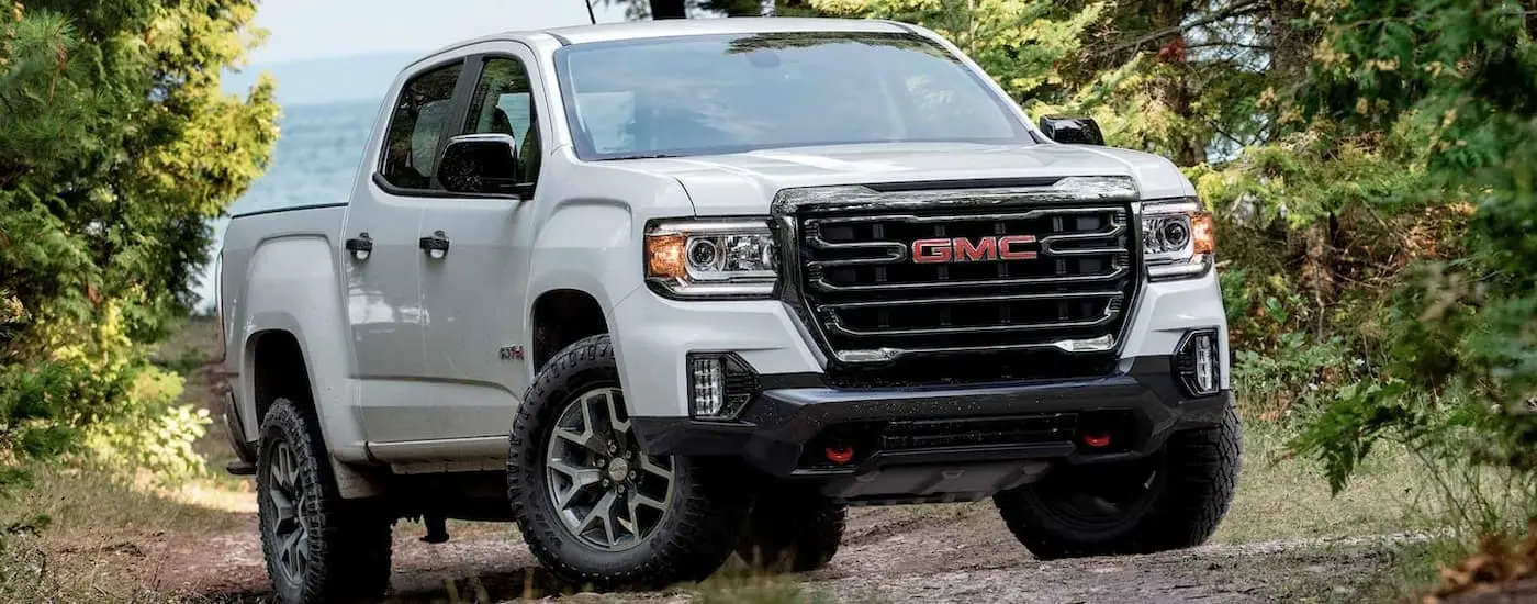 A white 2022 GMC Canyon AT4 is shown parked on a dirt road.