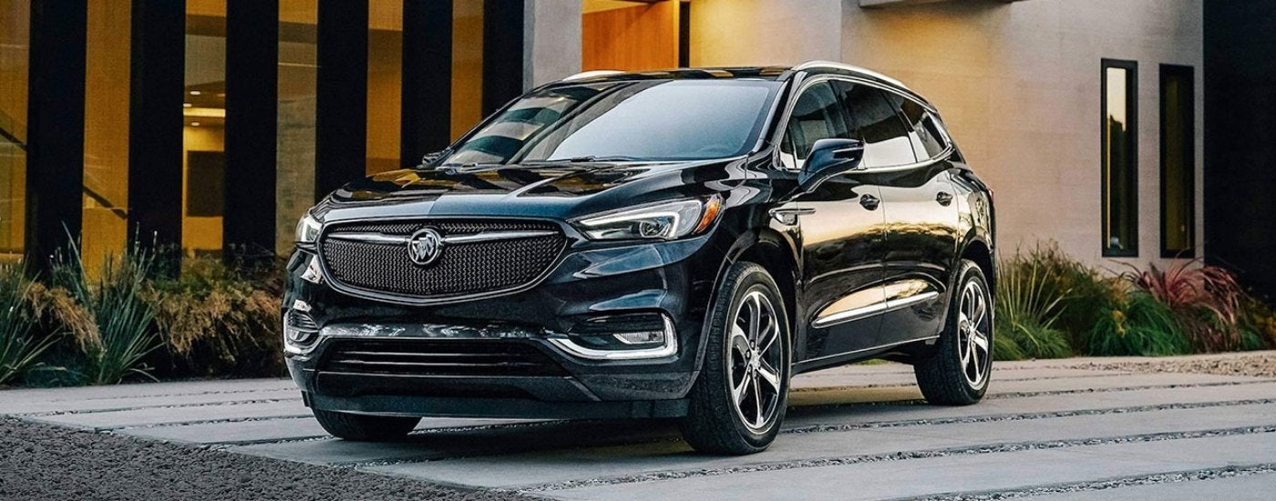 A black 2021 Buick Enclave parked on the driveway of a modern house.