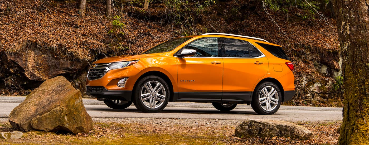 An orange 2019 Chevy Equinox driving from a dealer with used cars for sale.